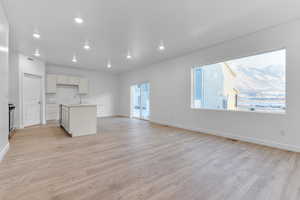 Interior space with a kitchen island with sink, sink, electric range, and light hardwood / wood-style flooring