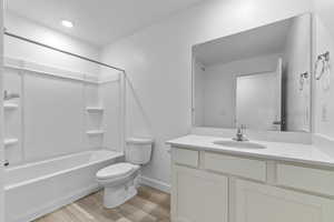 Full bathroom with hardwood / wood-style flooring, vanity, toilet, and  shower combination