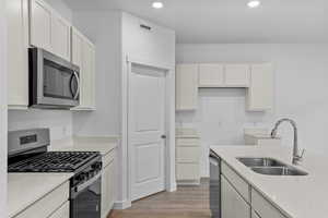 Kitchen with white cabinetry, sink, and appliances with stainless steel finishes