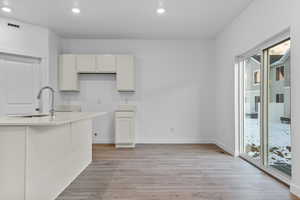 Kitchen with sink, white cabinets, and light hardwood / wood-style flooring