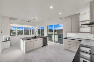 Kitchen with dishwasher, sink, decorative backsplash, hanging light fixtures, and wall chimney range hood