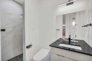 Bathroom with a shower, vanity, and toilet