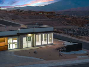 Back house at dusk featuring a mountain view and a patio area