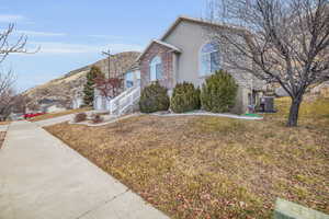 View of side of property with a garage, central AC, and a lawn