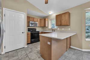 Kitchen featuring lofted ceiling, sink, kitchen peninsula, ceiling fan, and black range with electric stovetop