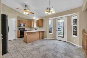 Kitchen with vaulted ceiling, ceiling fan with notable chandelier, hanging light fixtures, kitchen peninsula, and stainless steel appliances