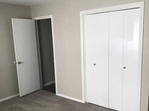 Unfurnished bedroom with dark carpet and a closet