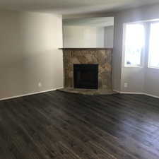 Unfurnished living room with a stone fireplace and dark hardwood / wood-style floors