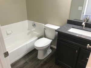 Bathroom with wood-type flooring, toilet, a bathing tub, and vanity