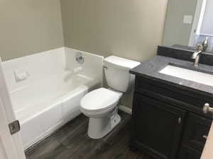 Bathroom with wood-type flooring, toilet, a bathtub, and vanity