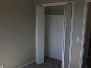 Unfurnished bedroom featuring dark carpet and a closet