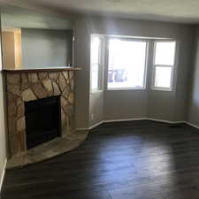 Unfurnished living room with dark wood-type flooring and a stone fireplace