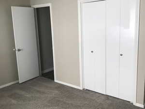 Unfurnished bedroom with dark carpet and a closet