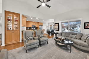 Living room featuring ceiling fan, high vaulted ceiling, and light wood-type flooring