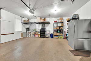 Garage featuring stainless steel refrigerator and a garage door opener