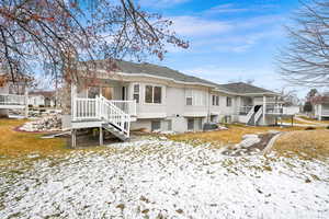 Snow covered back of property featuring central air condition unit and covered porch