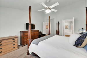 Bedroom featuring vaulted ceiling, light colored carpet, ceiling fan, and ensuite bath