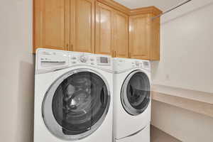 Laundry room featuring independent washer and dryer, cabinets, and tile patterned floors