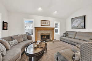 Living room with vaulted ceiling, plenty of natural light, carpet floors, and a fireplace