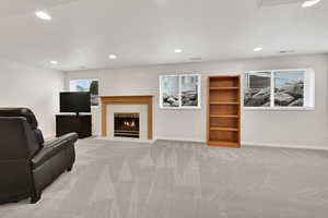 Unfurnished living room with a fireplace, light colored carpet, and a textured ceiling