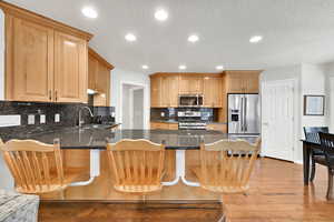 Kitchen featuring sink, a breakfast bar area, appliances with stainless steel finishes, kitchen peninsula, and light hardwood / wood-style floors