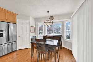 Dining space with a notable chandelier, light hardwood / wood-style flooring, and a textured ceiling