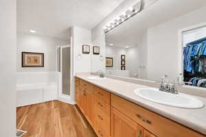 Bathroom featuring hardwood / wood-style flooring, vanity, plus walk in shower, and a textured ceiling