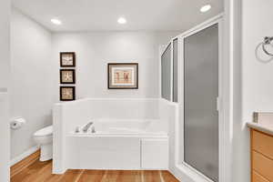 Full bathroom featuring hardwood / wood-style flooring, plus walk in shower, and toilet