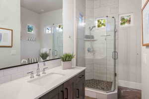 Bathroom featuring tasteful backsplash, vanity, and a shower with shower door