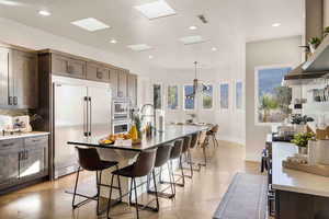 Kitchen with built in appliances, hanging light fixtures, a breakfast bar area, and an island with sink