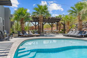 View of swimming pool with a pergola and a patio