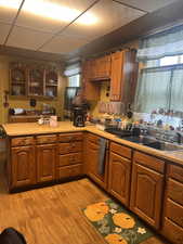 Kitchen with sink, a paneled ceiling, light hardwood / wood-style floors, and kitchen peninsula