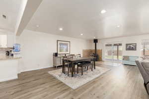 Dining room with a wood stove, a textured ceiling, and light hardwood / wood-style floors