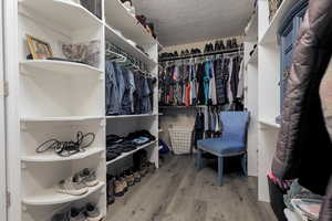 Walk in closet with hardwood / wood-style floors