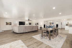 Dining area featuring a healthy amount of sunlight, ceiling fan with notable chandelier, a textured ceiling, and light wood-type flooring