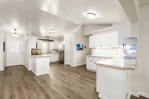 Kitchen featuring stainless steel refrigerator with ice dispenser, white cabinetry, kitchen peninsula, and sink