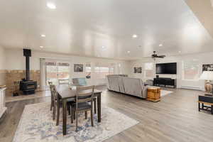 Dining space featuring a baseboard radiator, a wood stove, a textured ceiling, and light hardwood / wood-style floors