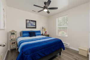 Bedroom with a baseboard heating unit, wood-type flooring, and ceiling fan