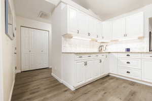 Kitchen with tasteful backsplash, light hardwood / wood-style floors, and white cabinets