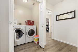 Washroom featuring washing machine and clothes dryer and light wood-type flooring