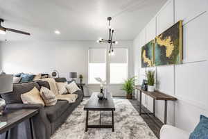 Living room featuring dark wood-type flooring and ceiling fan with notable chandelier