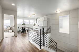 Hall with a textured ceiling and light hardwood / wood-style floors