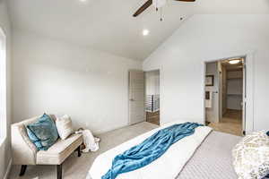 Carpeted bedroom with high vaulted ceiling, ceiling fan, and ensuite bathroom