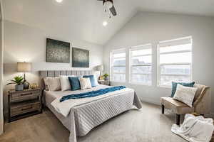 Carpeted bedroom with ceiling fan and vaulted ceiling