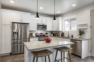 Kitchen with appliances with stainless steel finishes, decorative light fixtures, sink, and white cabinets