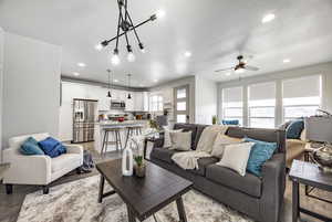 Living room with ceiling fan, a textured ceiling, and light wood-type flooring