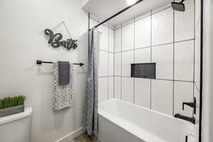 Bathroom featuring toilet, hardwood / wood-style floors, and shower / bath combo with shower curtain