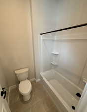 Bathroom featuring bathtub / shower combination, tile patterned floors, and toilet