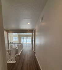 Hallway featuring dark hardwood / wood-style floors and a textured ceiling