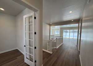 Hall featuring dark hardwood / wood-style flooring and a textured ceiling